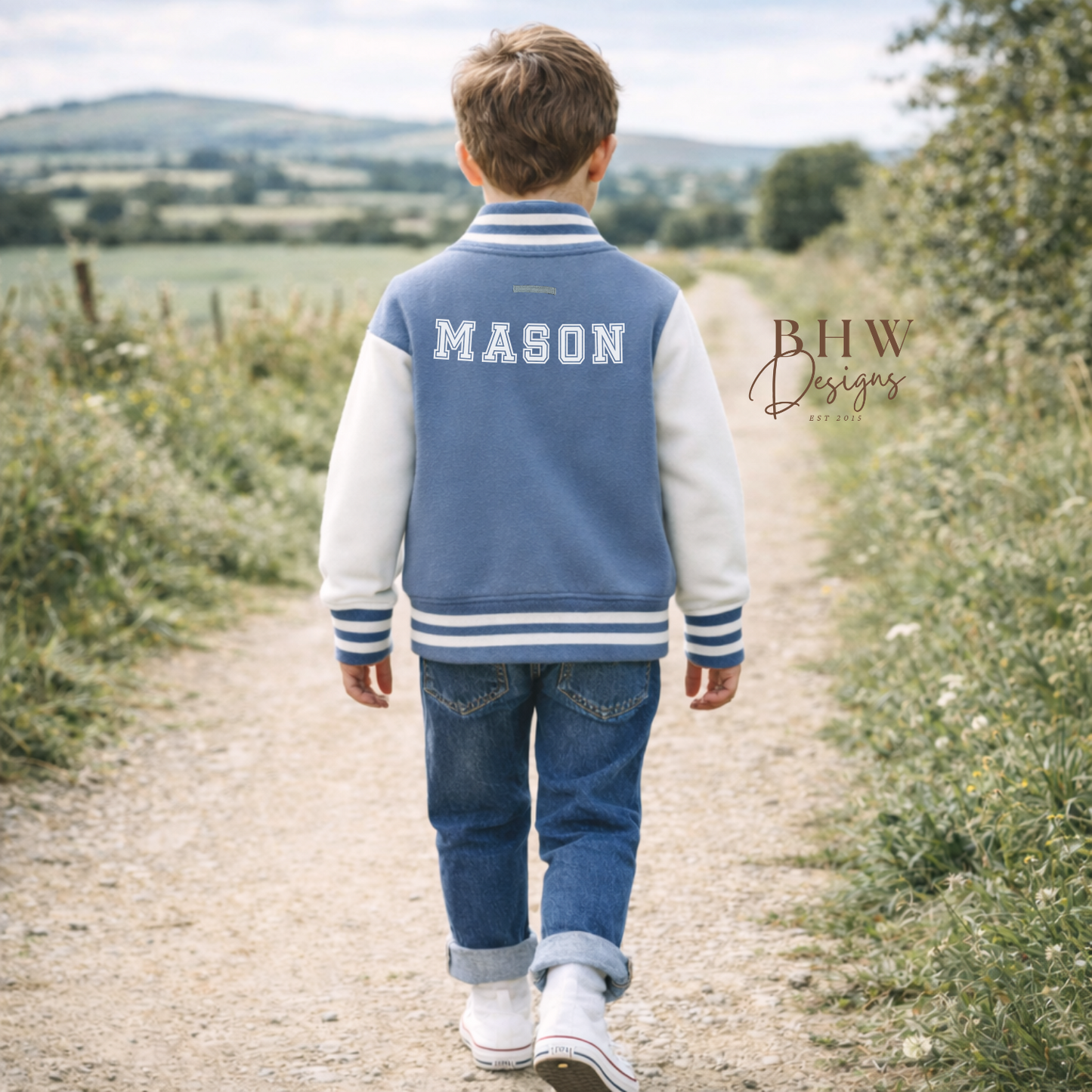 Child wearing a blue jacket with 'MASON' on it, walking on a path in a natural setting.