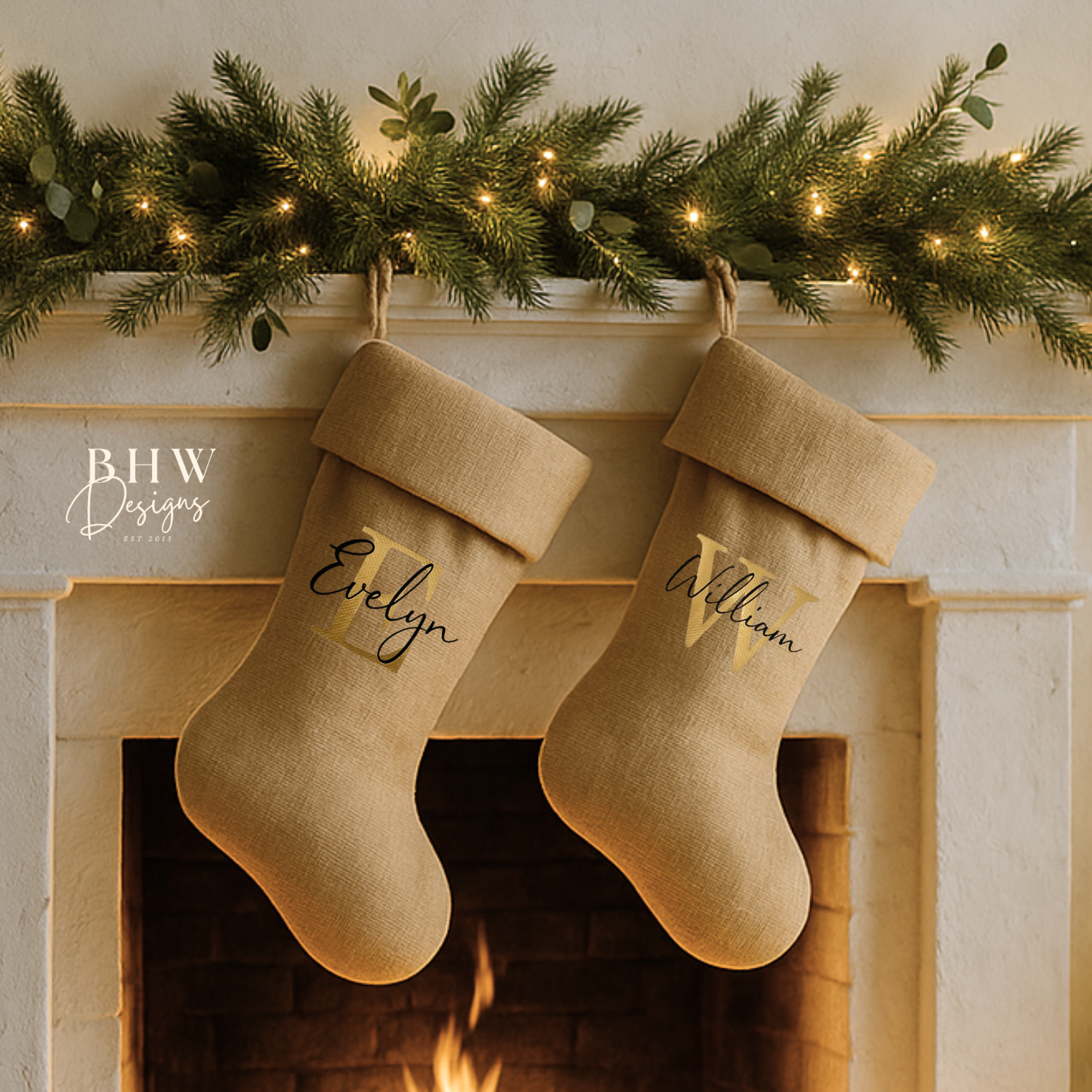 Two beige Personalised Christmas stockings hanging above a fireplace with names on them, decorated with a festive garland.