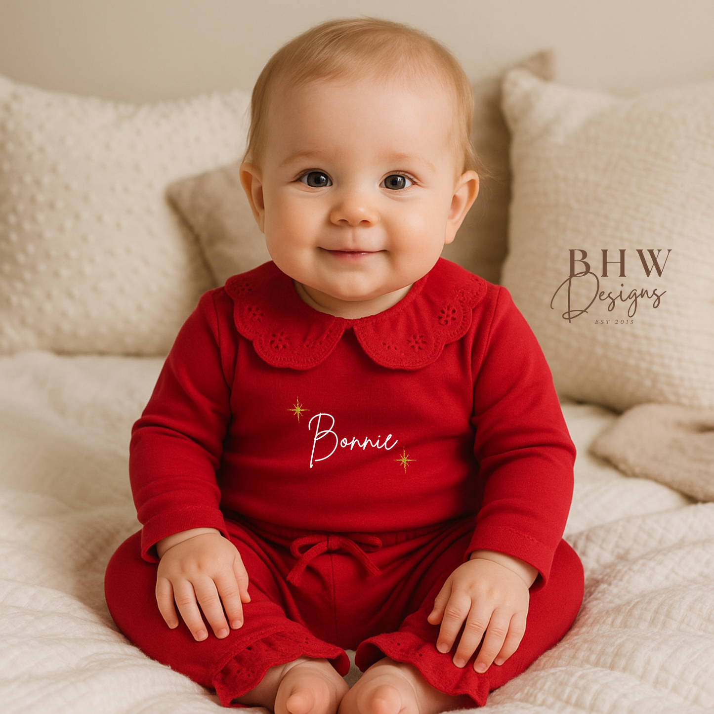 Baby wearing red pyjamas with lace detail collar personalised n white with gold glitter stars 