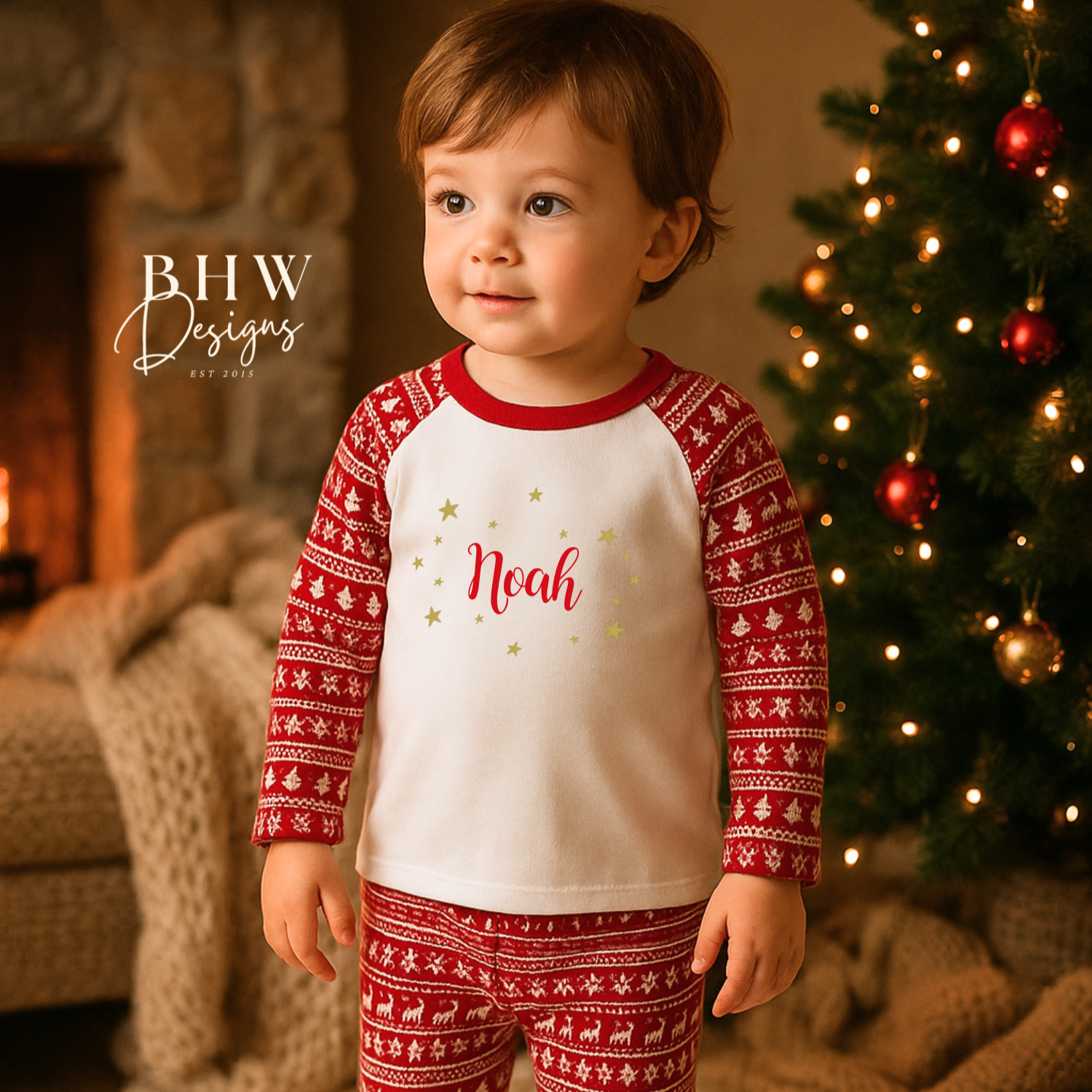 Child wearing red and white fair isle print pyjamas with 'Noah' printed on them, with gold stars