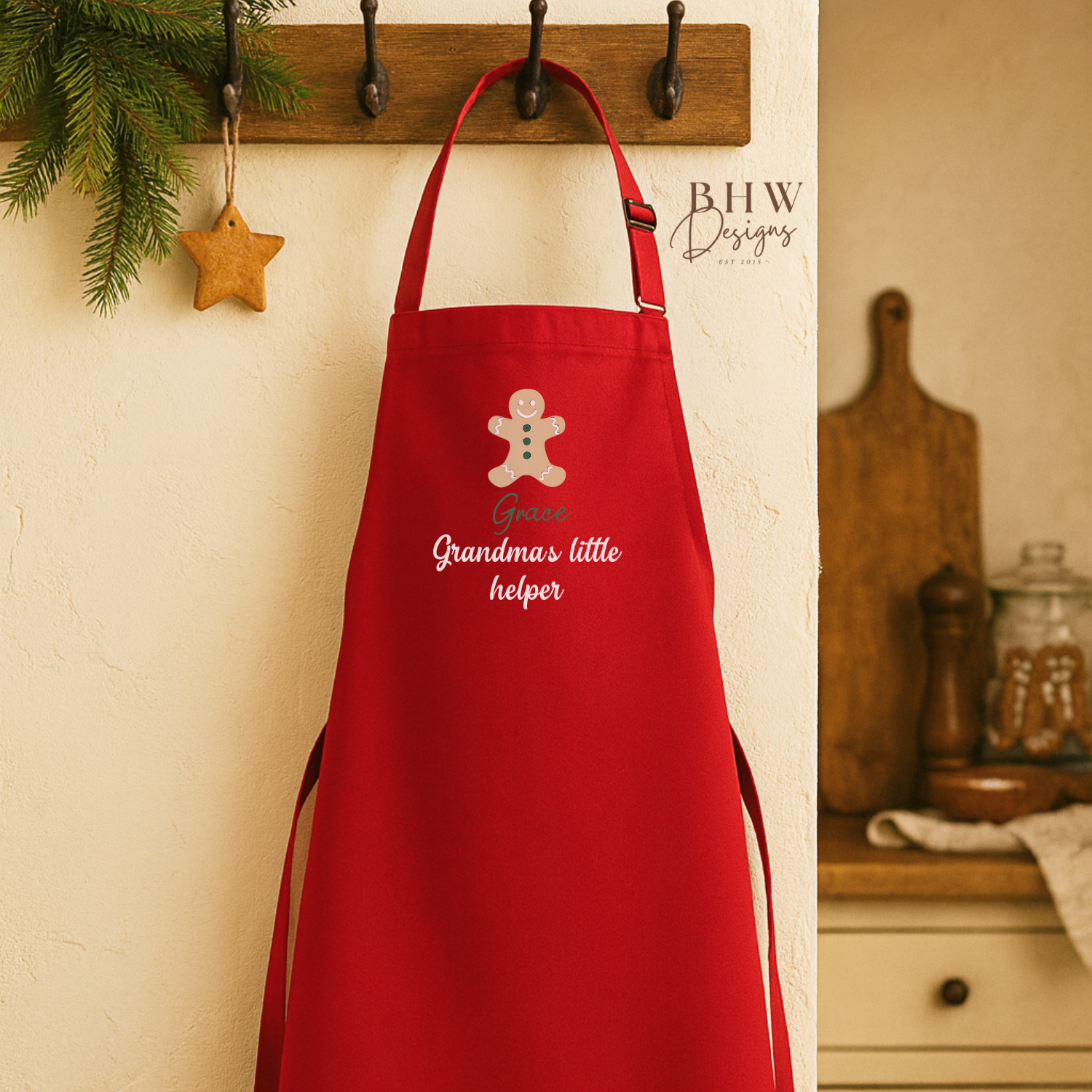 Red apron personalised and gingerbread man design hanging on a wall with kitchen background.