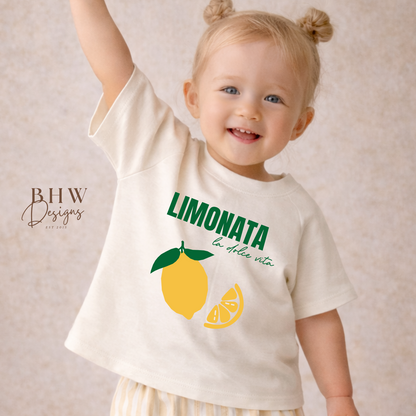 Child wearing a 'Limonata' t-shirt with lemon graphics on a beige background