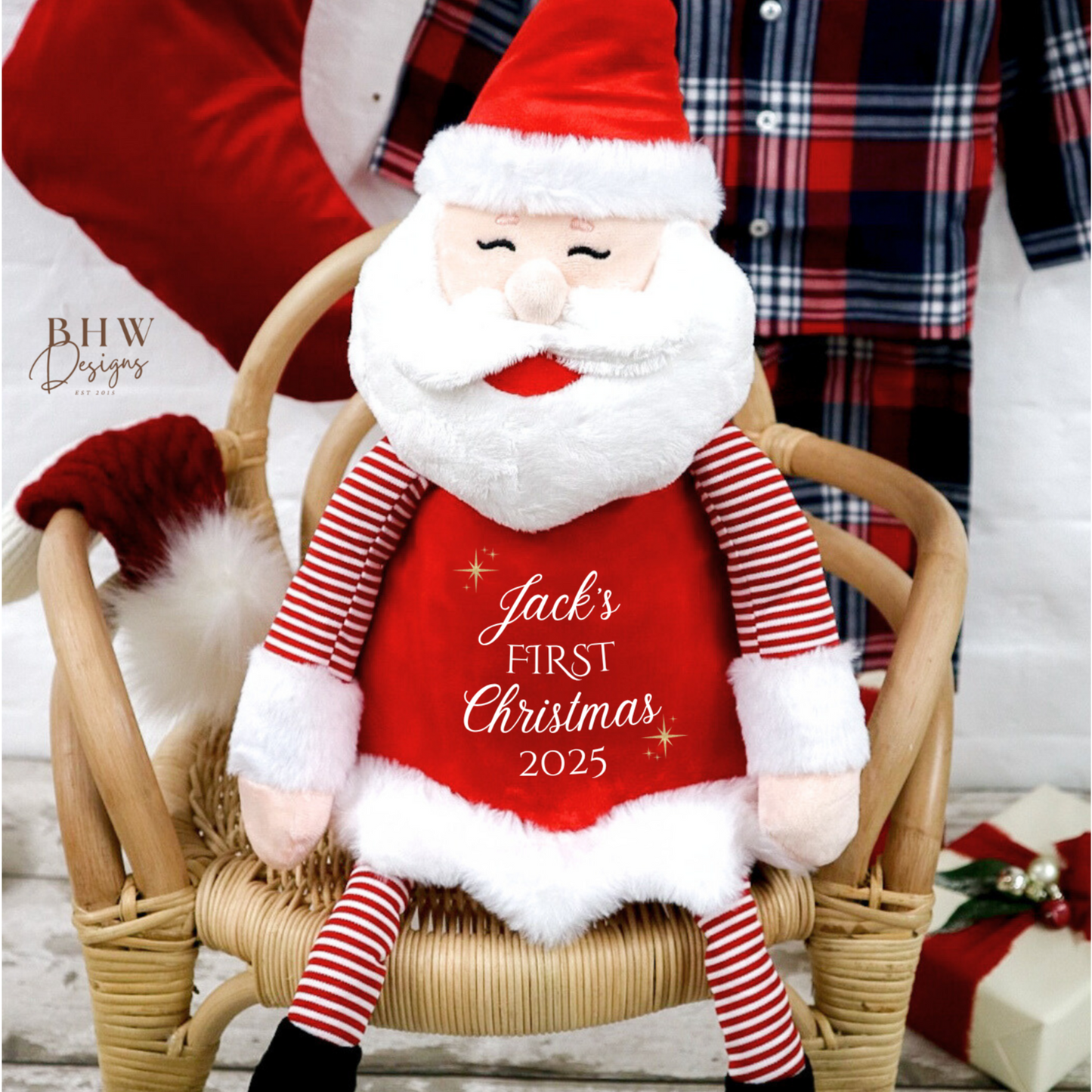 Plush Santa Claus toy with 'Jack's First Christmas 2025' text on a wooden chair.