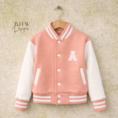 peach Pink varsity jacket with white sleeves on a hanger against a textured beige background,