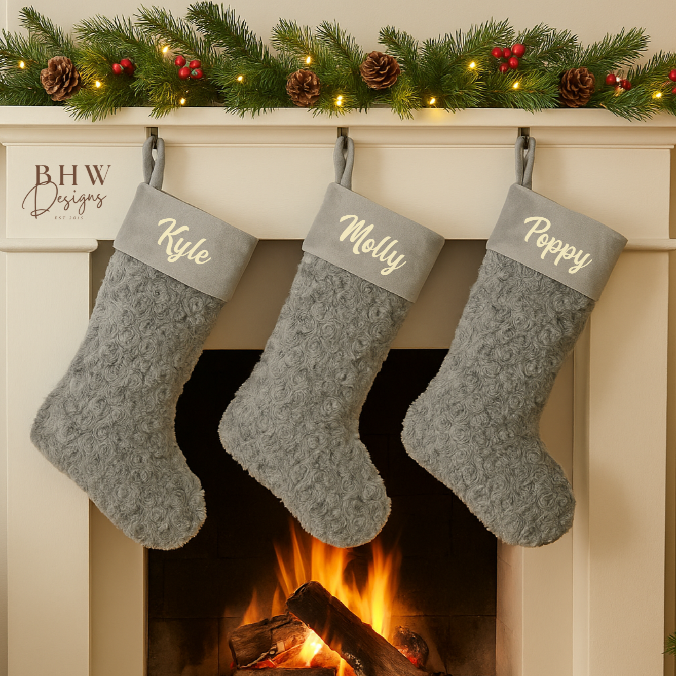Three grey Christmas stockings with names hanging in front of a fireplace.