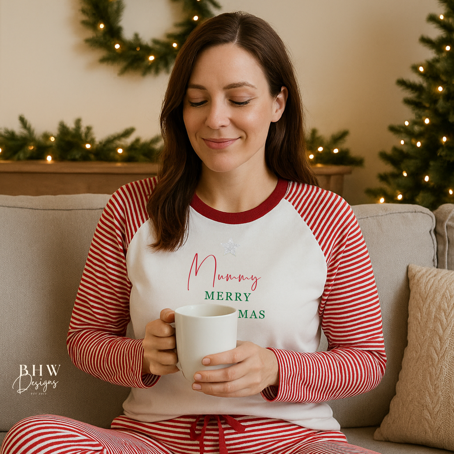 Woman wearing red and white striped pyjamas personalised on the front with a silver glitter star and a name in red and merry Christmas in green, sitting on a couch
