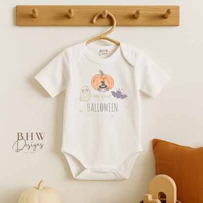 Baby onesie with My First Halloween design on a hanger against a neutral wall.