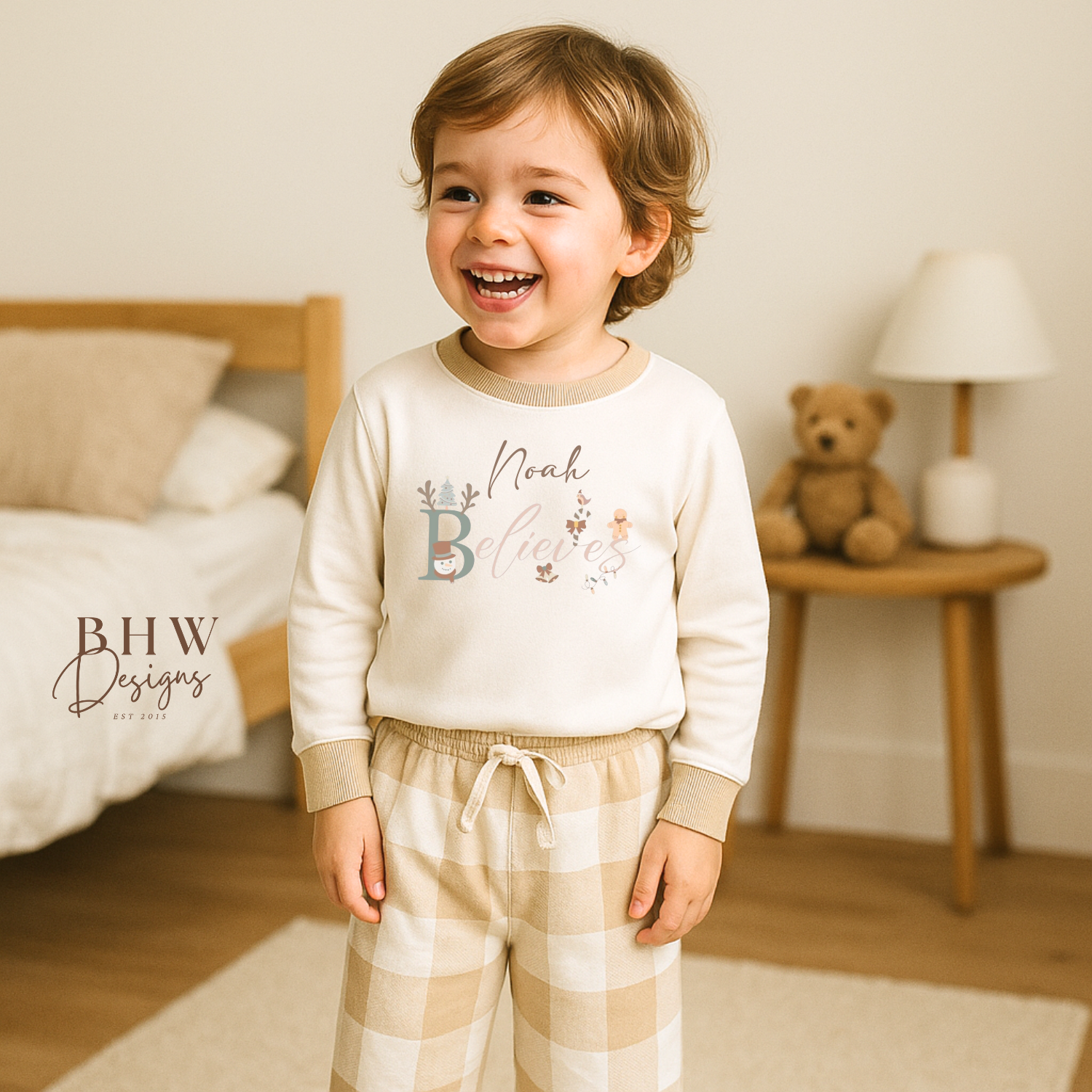 Child wearing a white long-sleeve top with beige cuffs personalised on the front with believes and beige and white check trousers