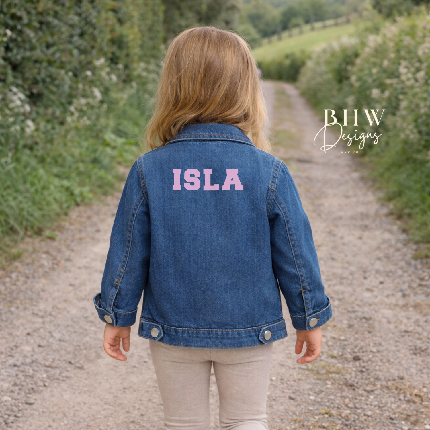 Child wearing a blue denim jacket with 'ISLA' on the back in baby pink