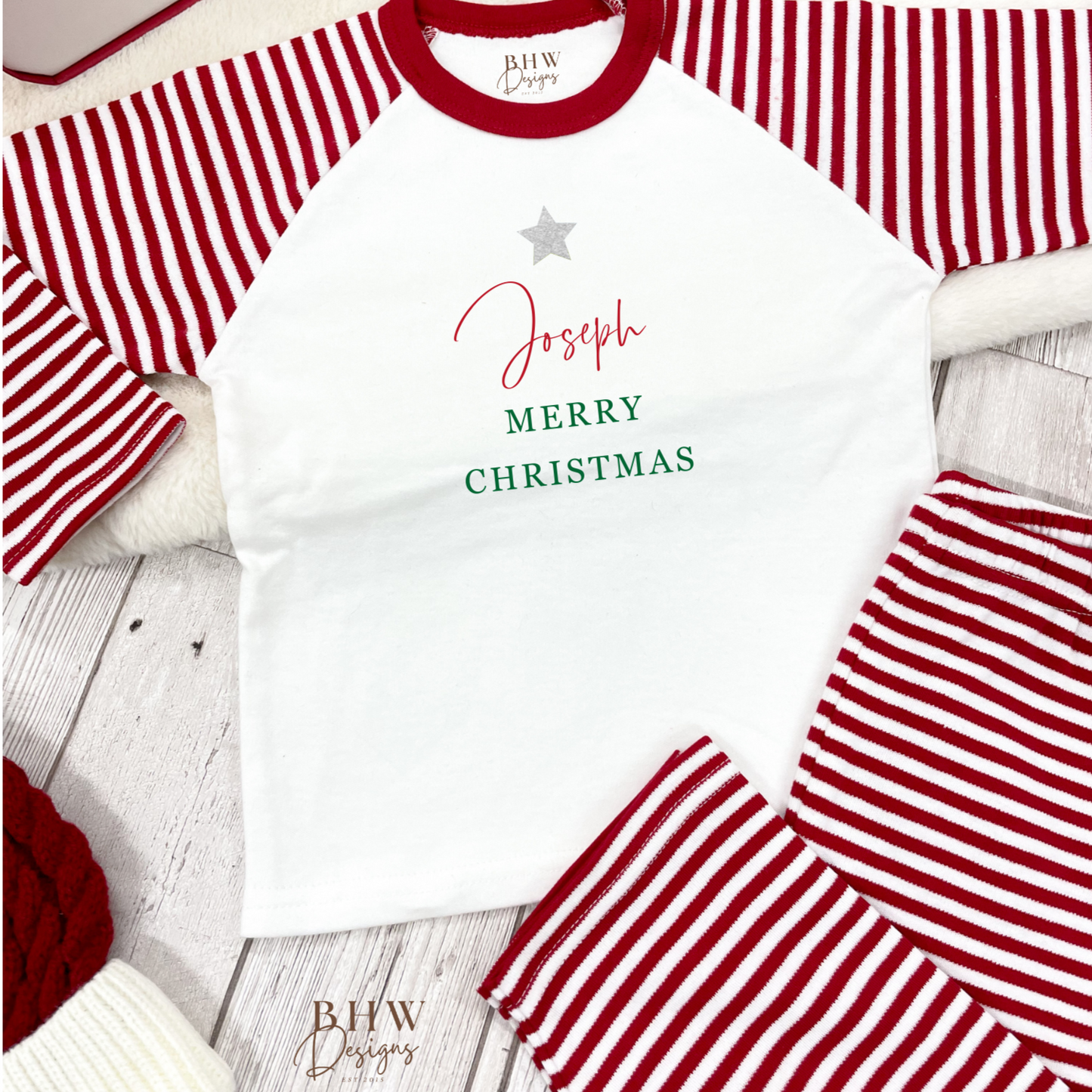 Children's red and white striped pajama set with 'Merry Christmas' text on a wooden surface.
