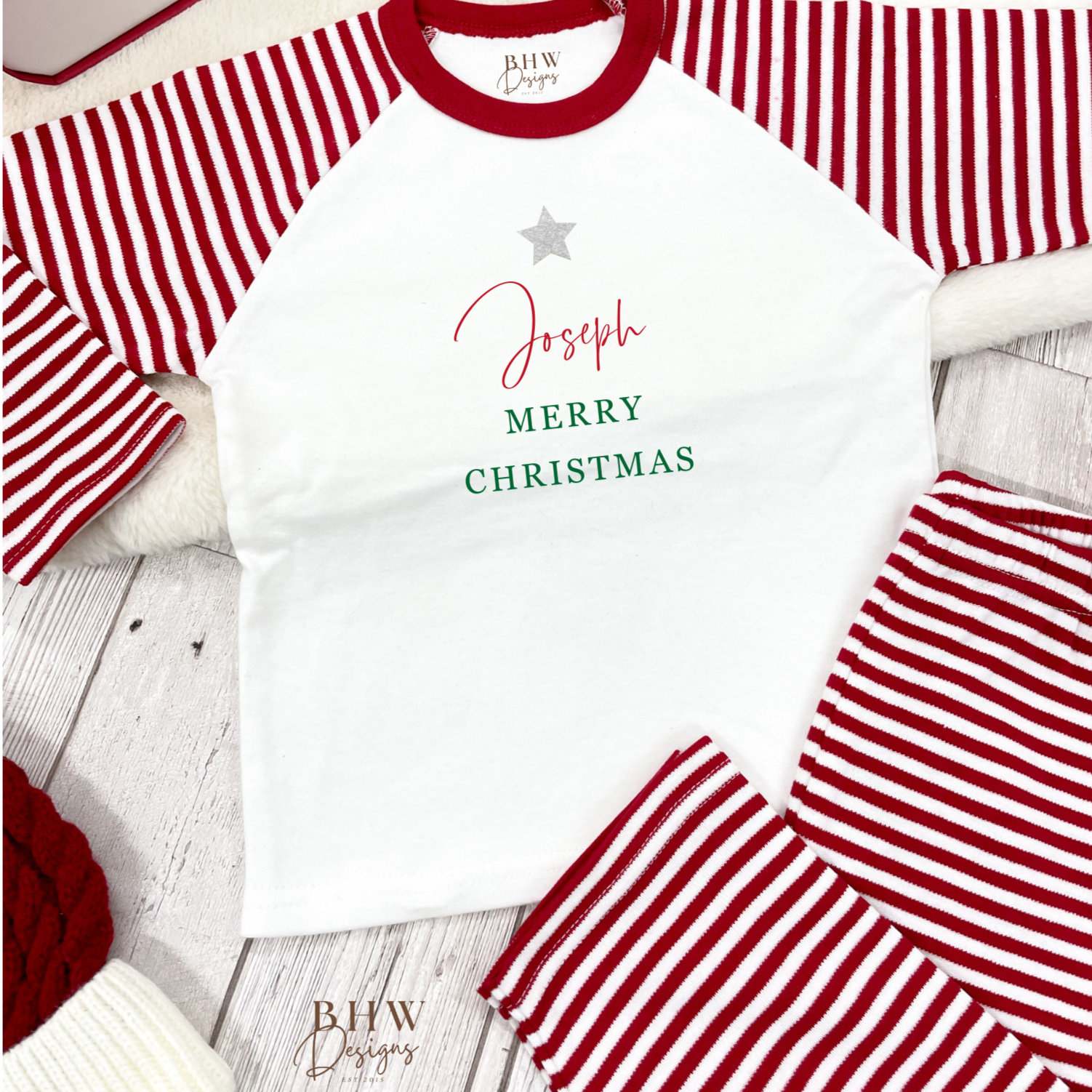 Children's red and white striped pajama set with 'Merry Christmas' text on a wooden surface.