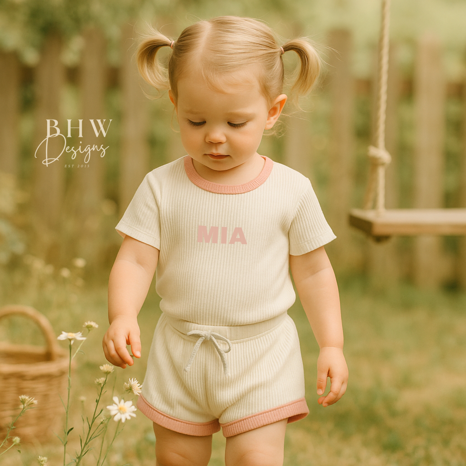 Girl wearing a white ribbed t shirt and short set with 'MIA' printed on the front in baby pink