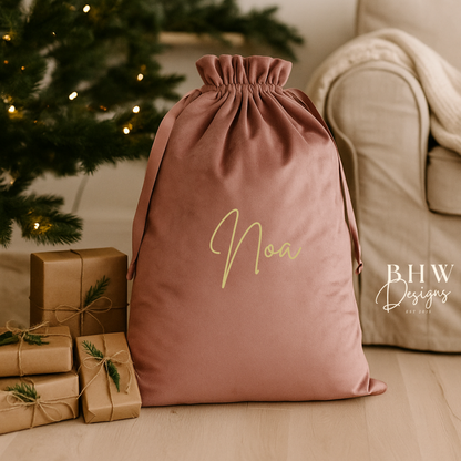 Pink drawstring bag with 'Noa' written on it, surrounded by Christmas decorations.