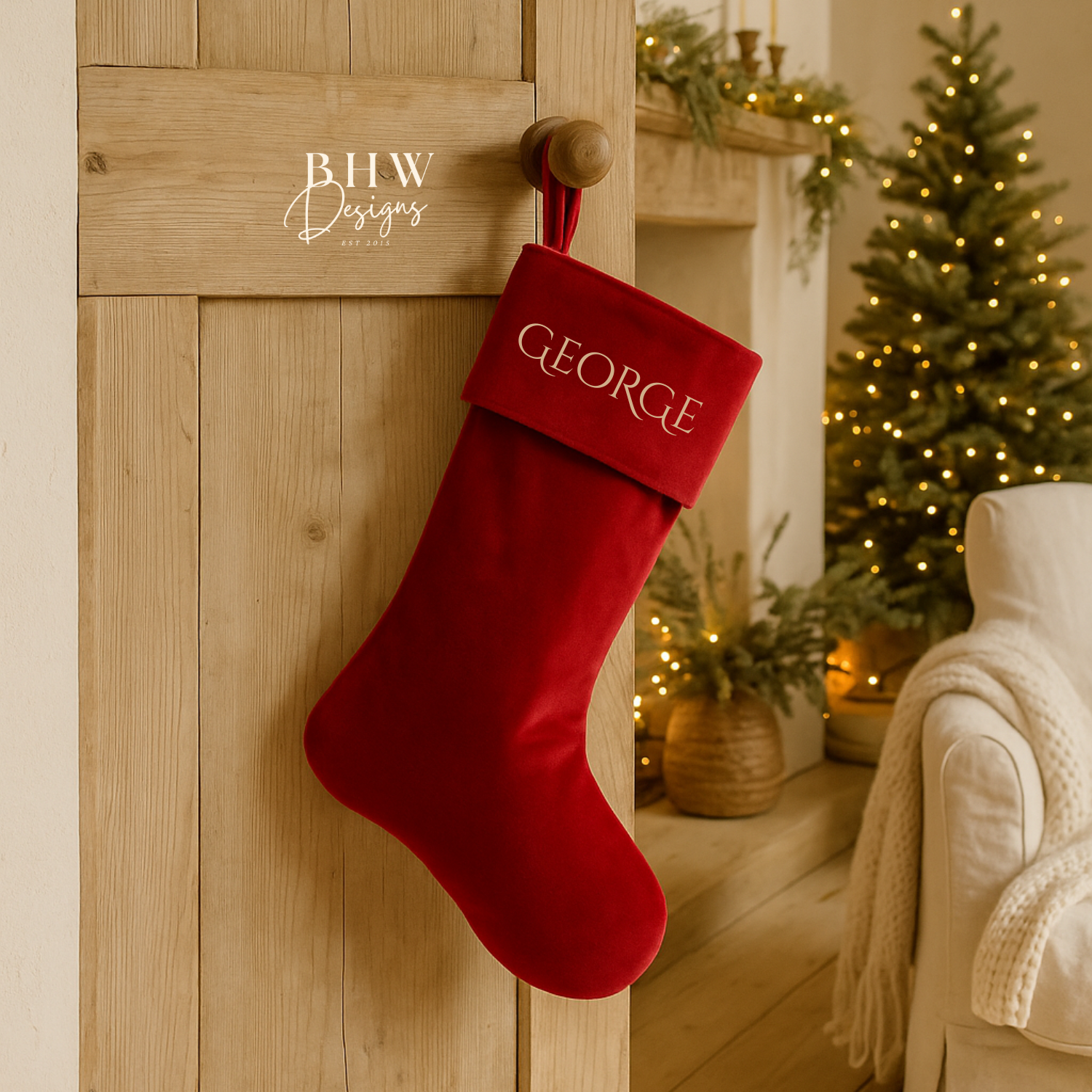 Red Christmas stocking with 'GEORGE' on the front hanging on a wooden door, festive decorations in the background.