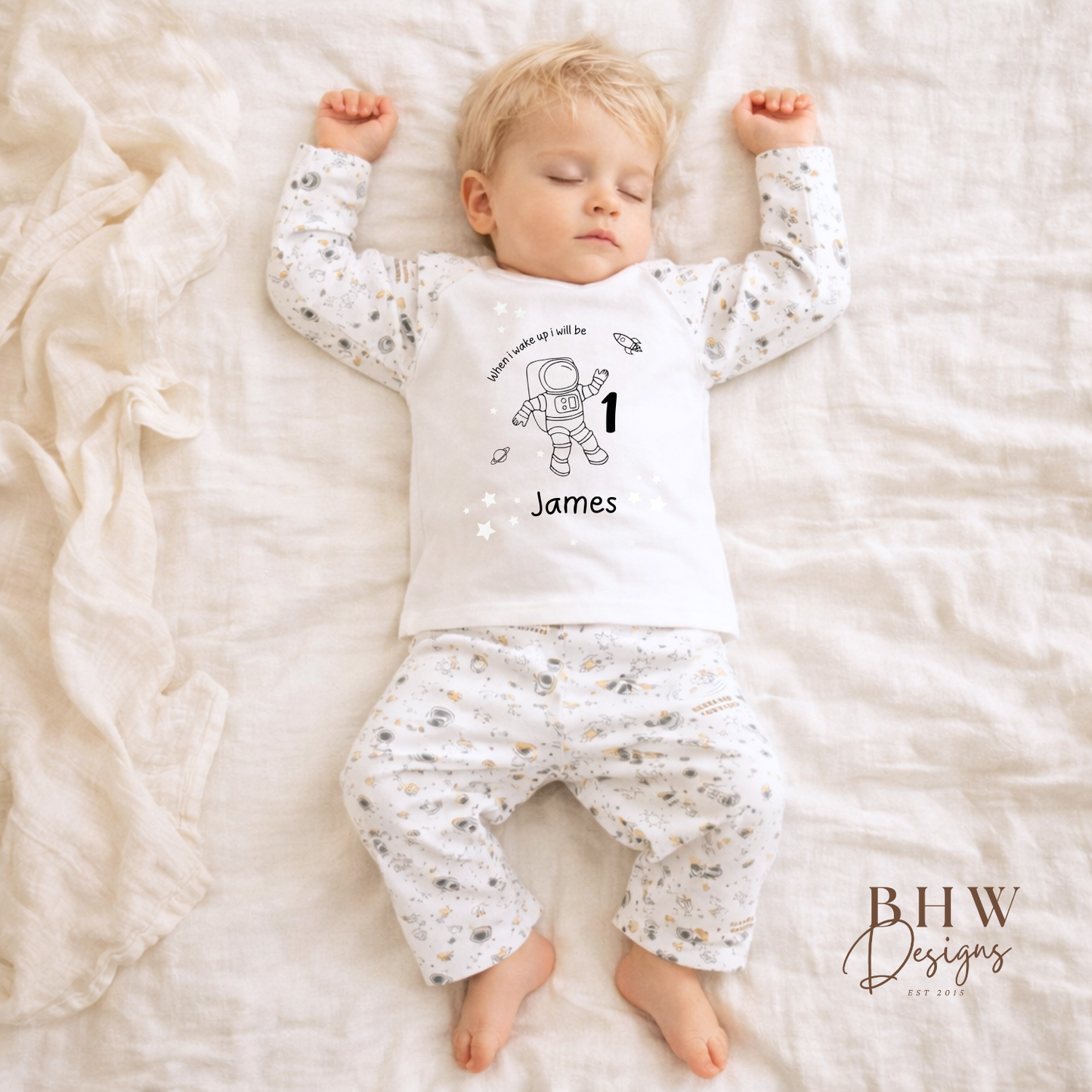 Baby in a white outfit with space-themed design and personalised with name and age