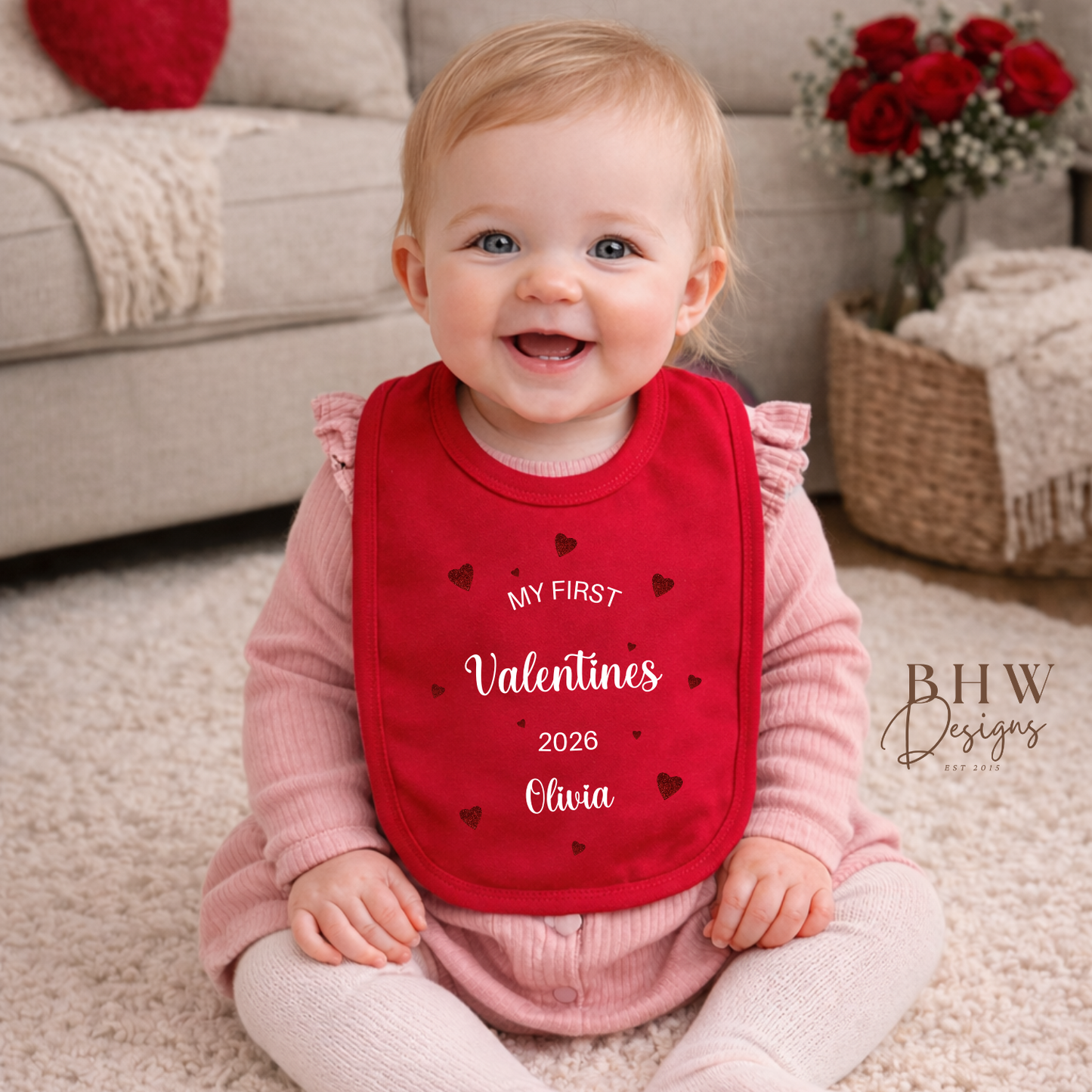 Baby wearing a red 'My First Valentine's 2026' bib sitting on a carpeted floor.