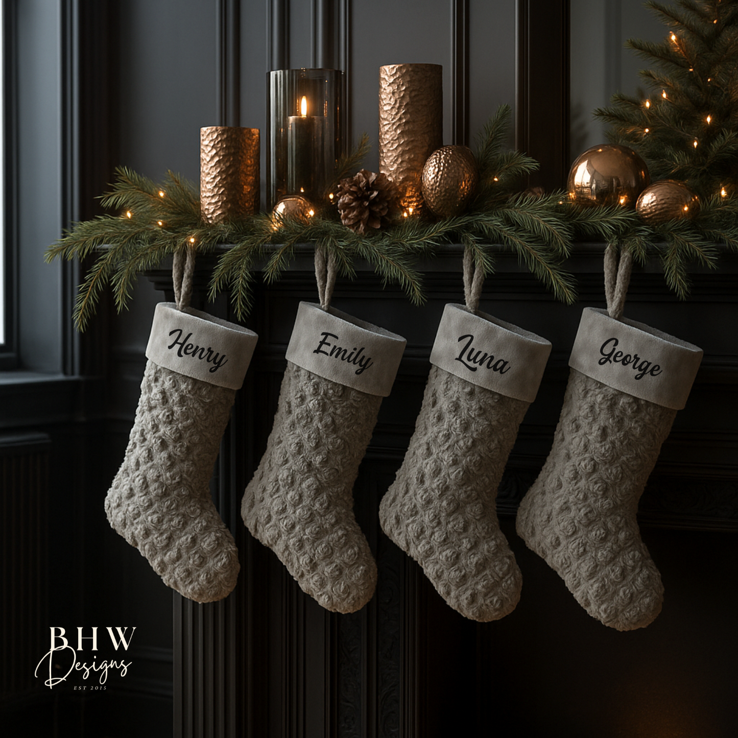 four textured personalised Christmas stockings hanging on a fireplace mantel with decorative candles and greenery.