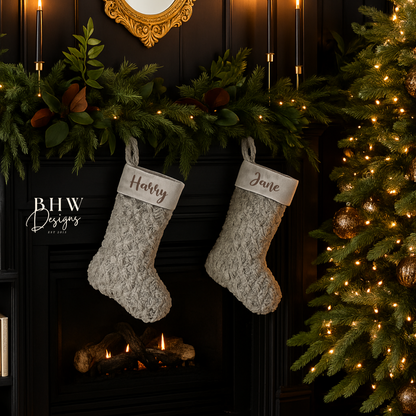 Two personalised Christmas stockings hanging above a fireplace with decorative lights and a tree.