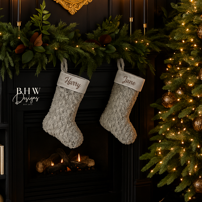 Two Grey personalised Christmas stockings hanging above a fireplace with decorative lights and a tree.