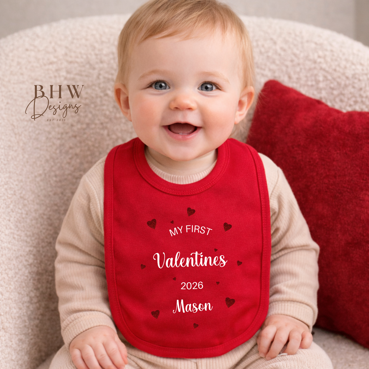 Baby wearing a red 'My First Valentine's 2026' bib sitting on a cushion.