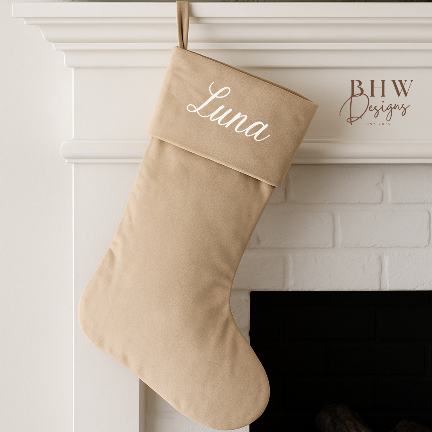 Beige Christmas stocking with 'Luna'  on it, hanging above a fireplace.