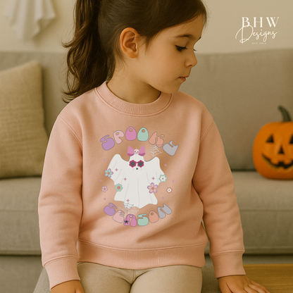 Child wearing a pink sweatshirt with spooky season ghost design on the front 