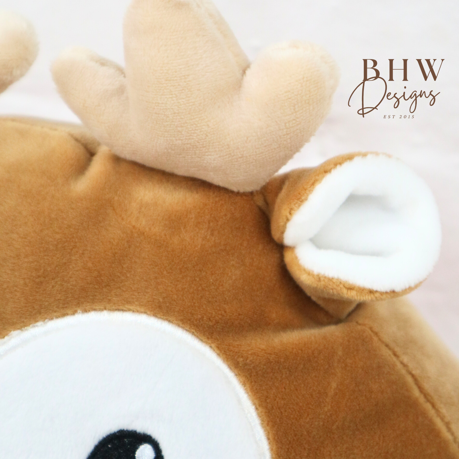 Close-up of a plush reindeer toy with 'BHW Designs' branding.