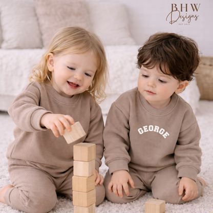 Two children playing with wooden blocks on a carpeted floor wearing taupe personalised waffle lounge set