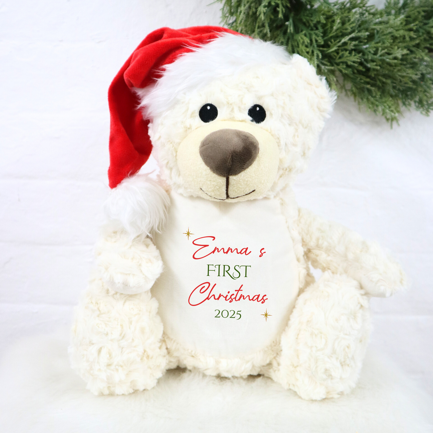 White teddy bear wearing a red Santa hat with 'Emma's First Christmas 2025' text on a white background.