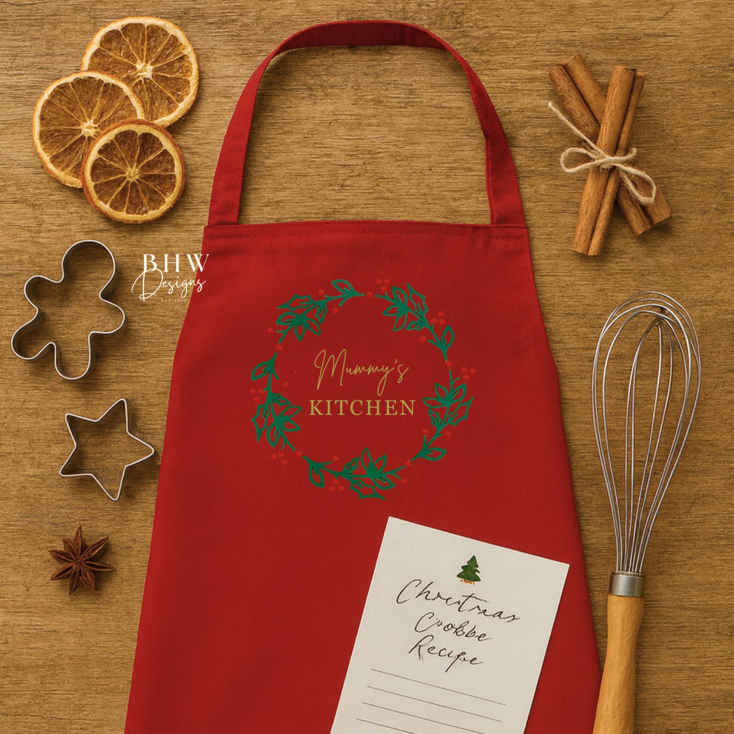 Red apron with Christmas design on a wooden surface with baking items.