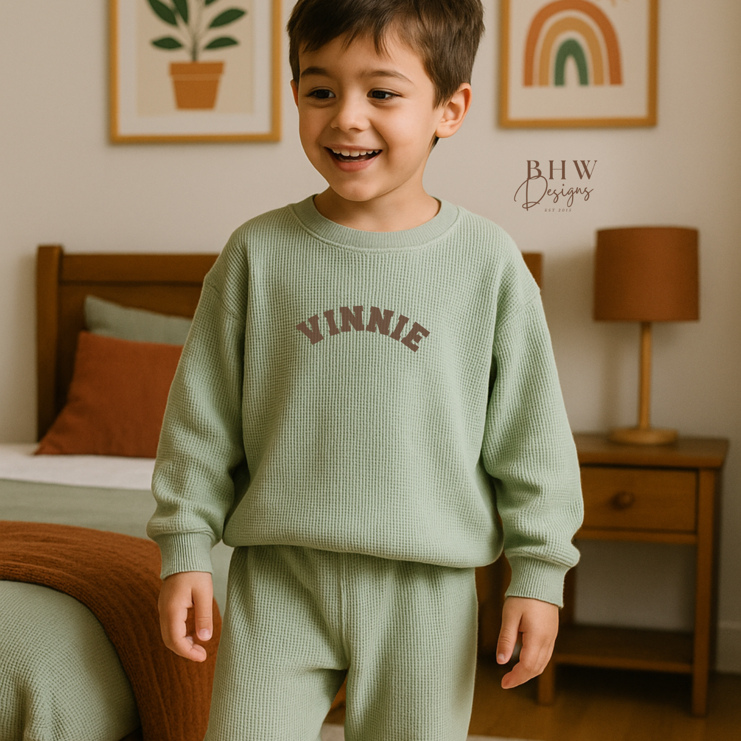 Child wearing a green 'Vinnie' sweater and pants in a bedroom setting