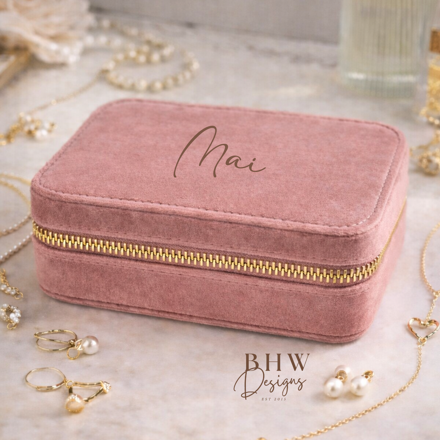 Pink velvet jewellery box with gold zipper on a marble surface,