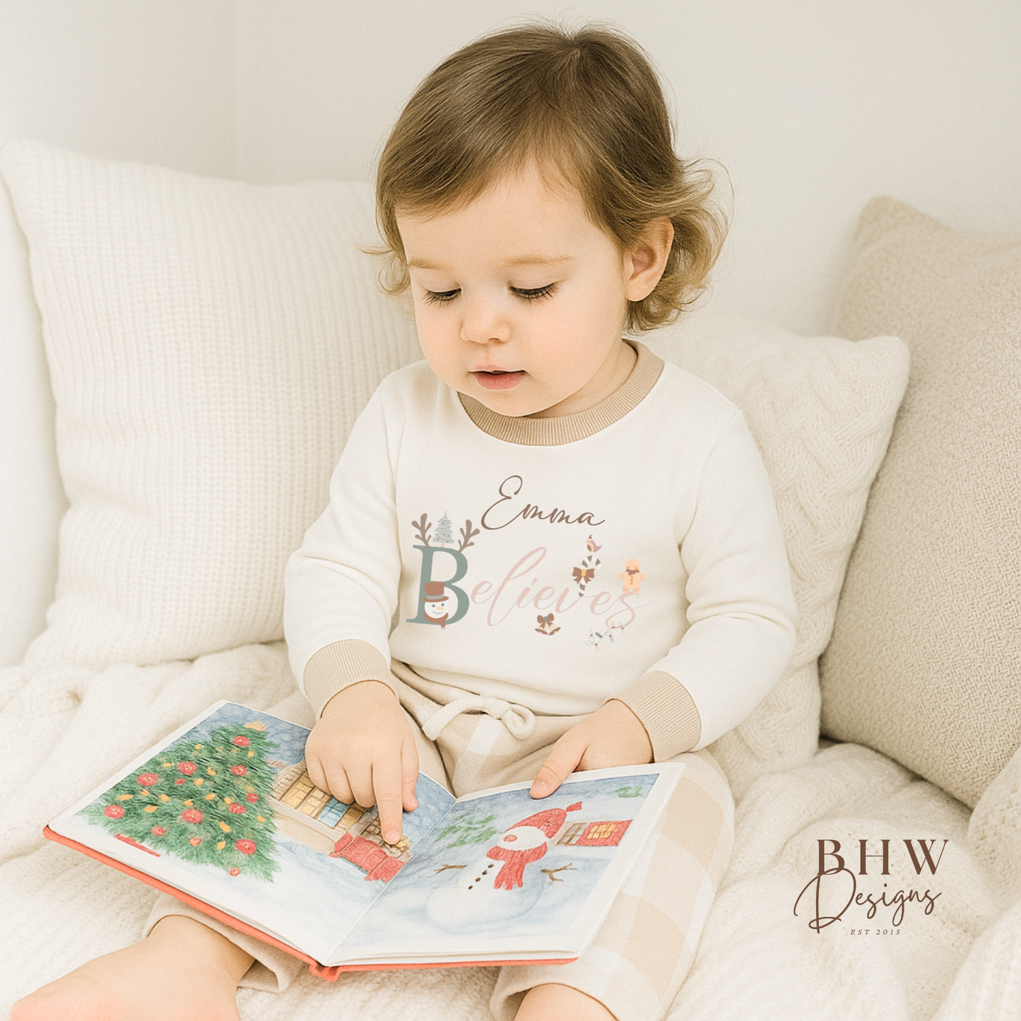 Child wearing a white long-sleeve top with beige cuffs personalised on the front with believes and beige and white check trousers