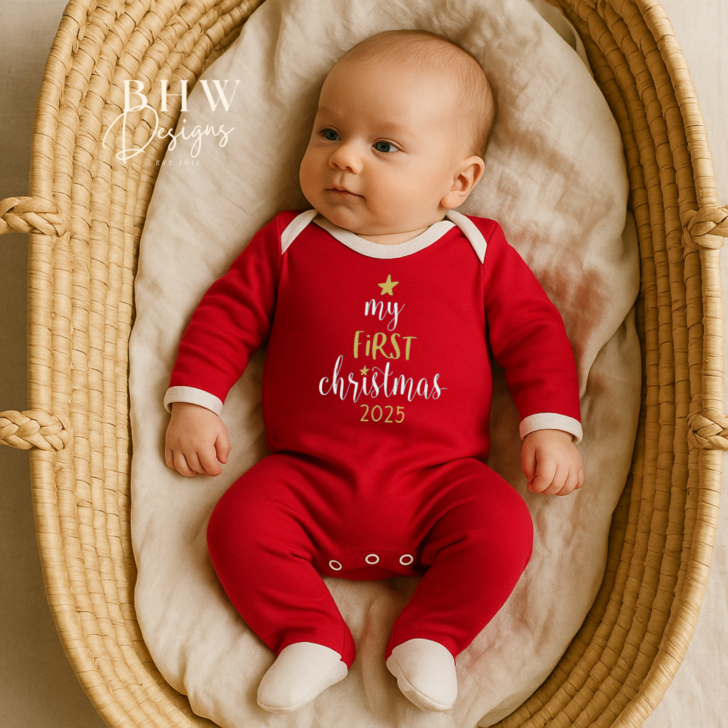 Baby in a red 'My First Christmas 2025' onesie lying in a woven basket.