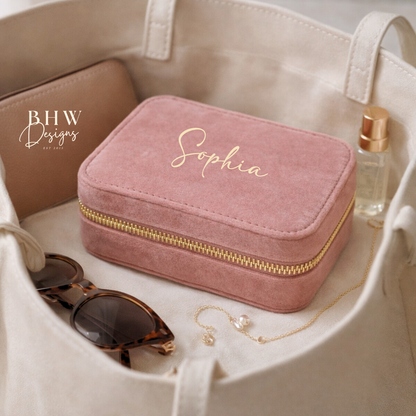 Pink jewellery box with 'Sophia' on the front a beige bag with sunglasses and a bottle of perfume.