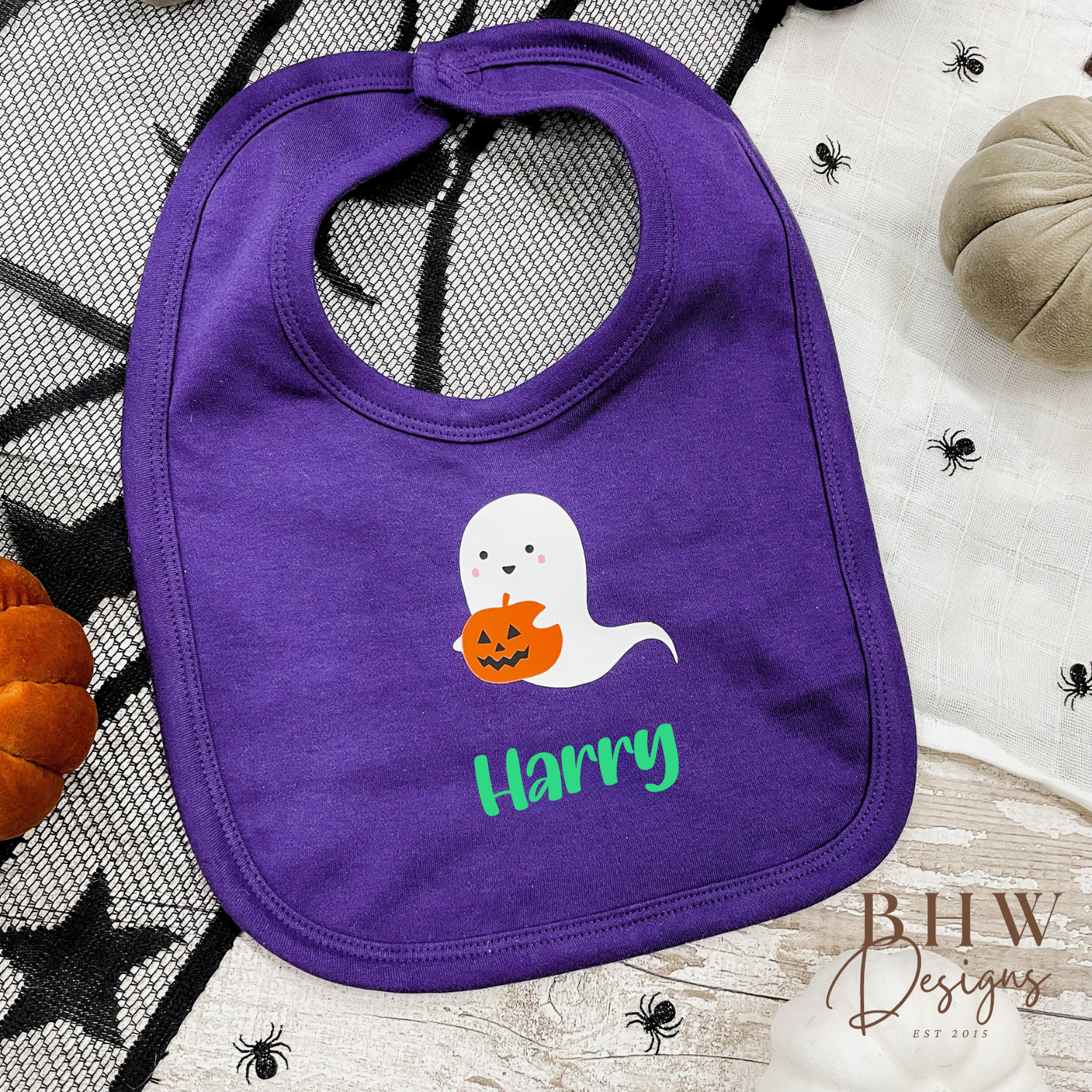 Personalised Purple bib with ghost and pumpkin design, with name 'Harry', on a Halloween-themed background.