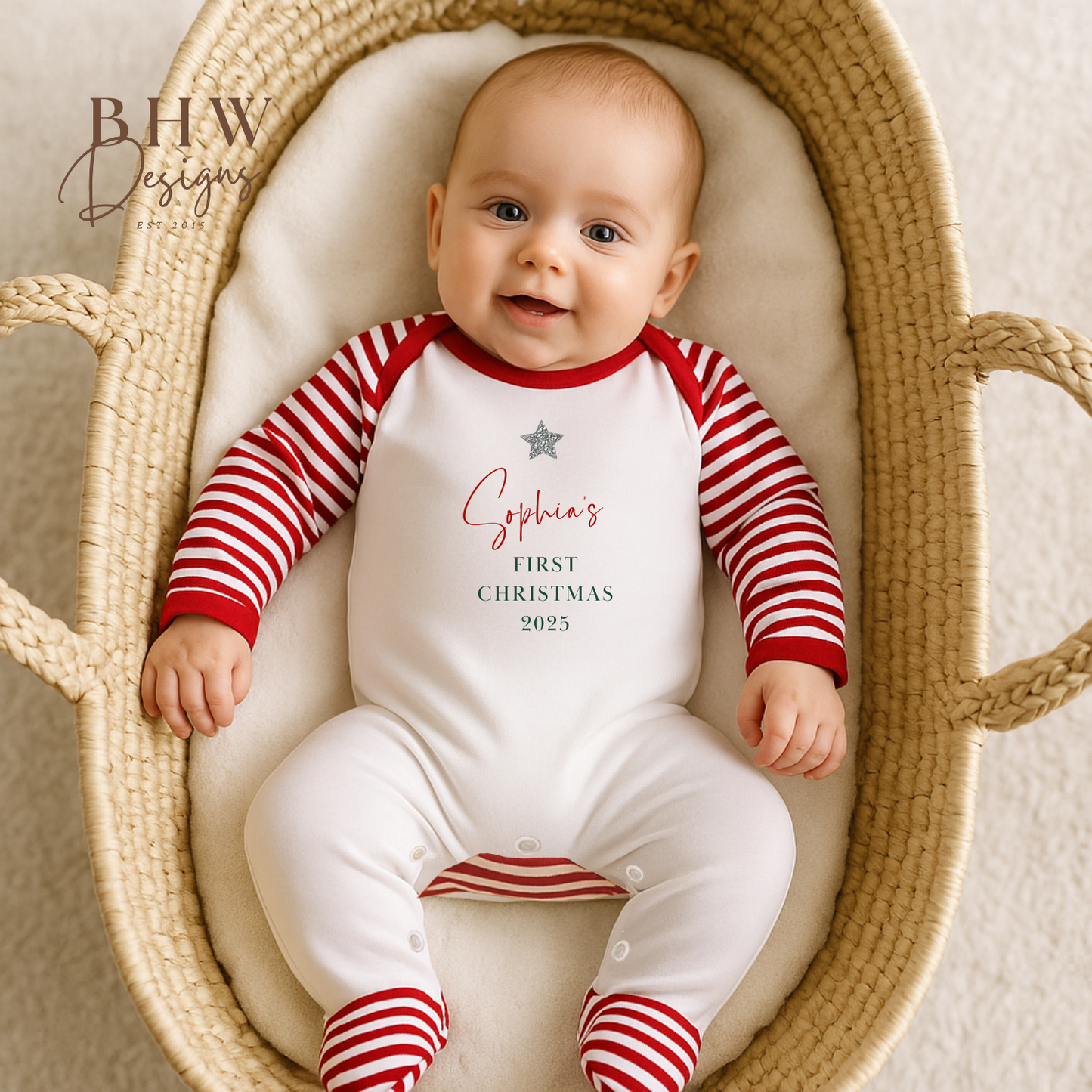 Baby in a striped outfit with 'Sophia's First Christmas 2025' text, lying in a woven basket.