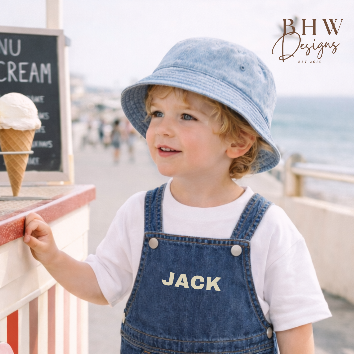 Child wearing a denim hat and overalls with 'JACK' on