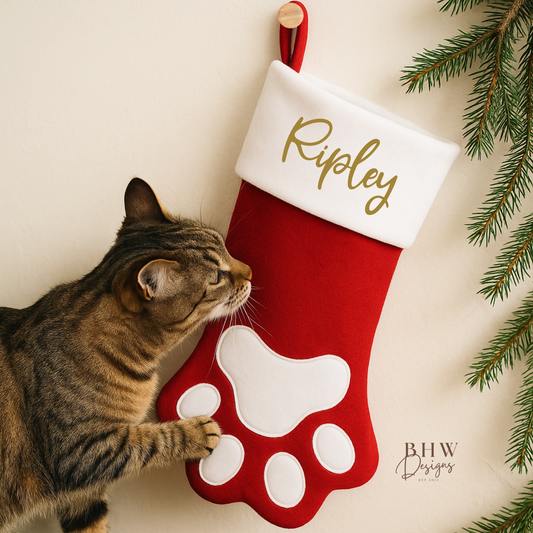 Cat interacting with a red and white Christmas stocking in a paw shape design personalised with Ripley in Gold