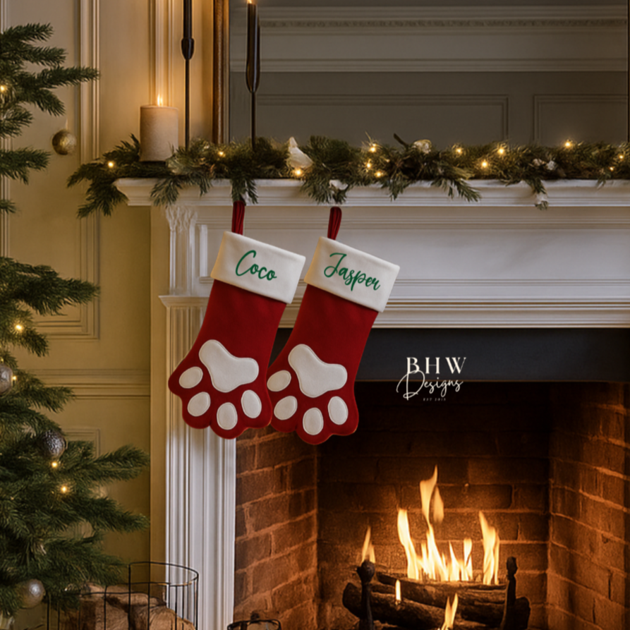  a fireplace with two red and white paw shape Christmas stockings with Coco and Jasper in green and decorations.