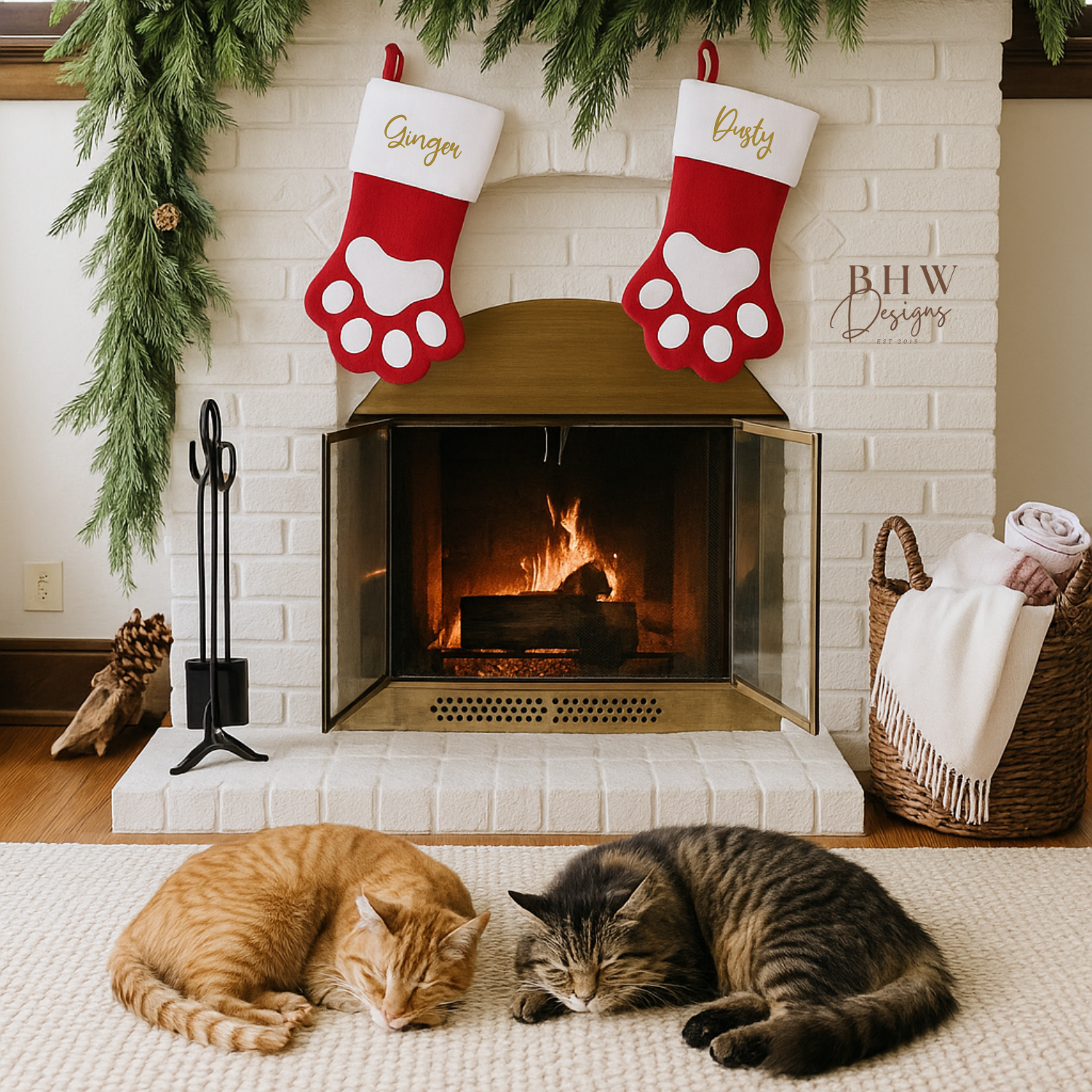 Two cats lying in front of a fireplace with red and white paw shape Christmas stockings personalised with Ginger and Dusty in gold 