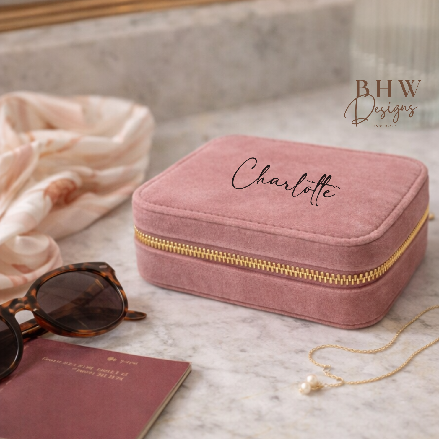 Pink jewellery box with 'Charlotte' on a marble surface with sunglasses 