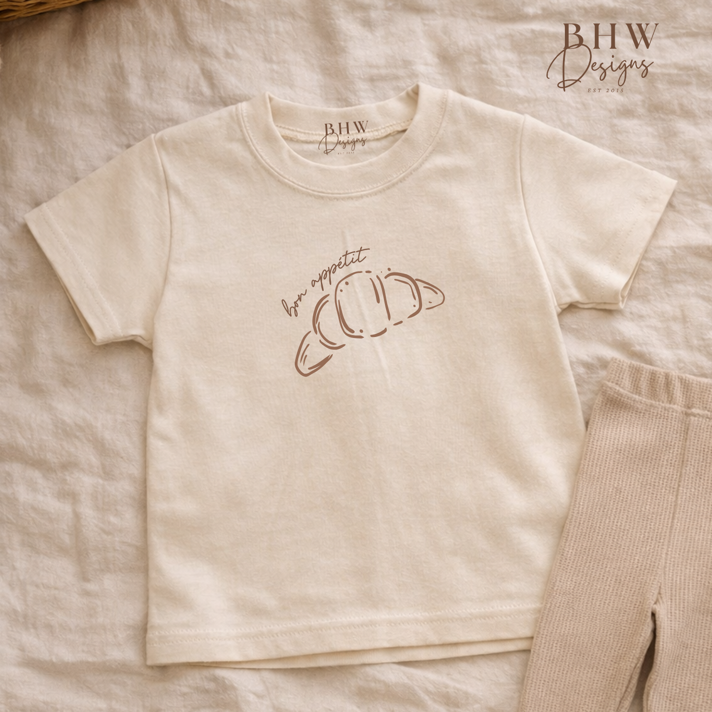 Beige t-shirt, with Bon Appétit Croissant design on there front 