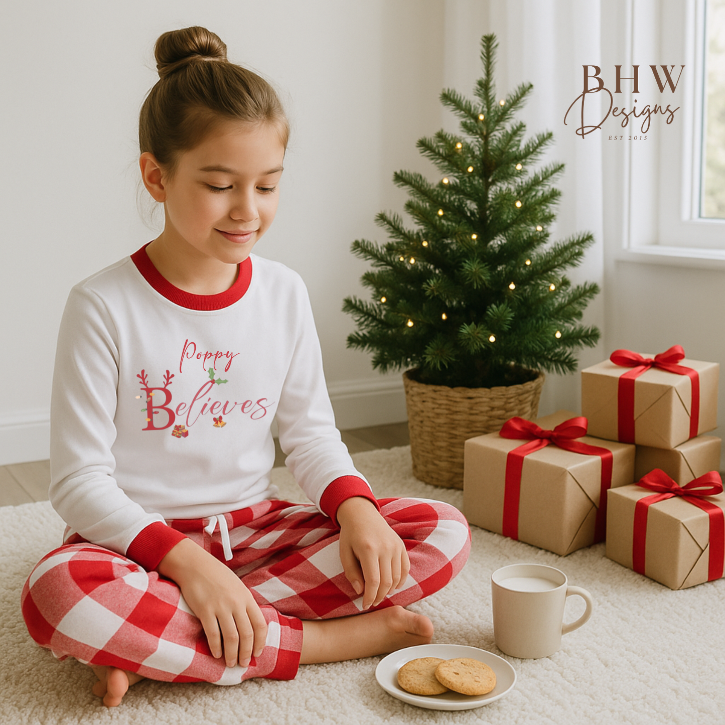 Young girl in Christmas pajamas sitting on the floor with a decorated tree and presents.