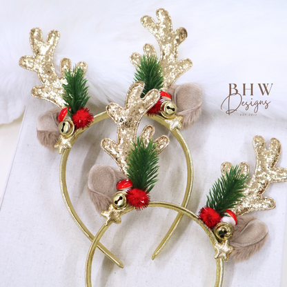 Gold reindeer headband with green leaves and red berries on a white background