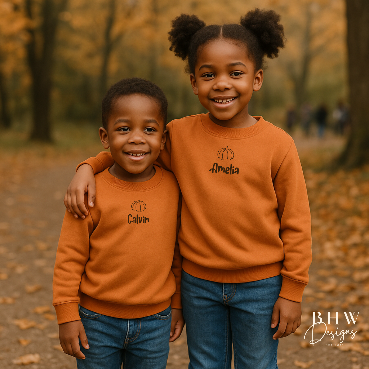 Two children wearing matching personalised rust orange sweatshirts with names in an autumn setting.