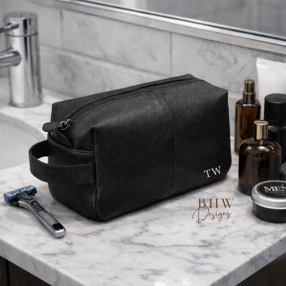 Black toiletry bag on a marble bathroom counter with grooming products.