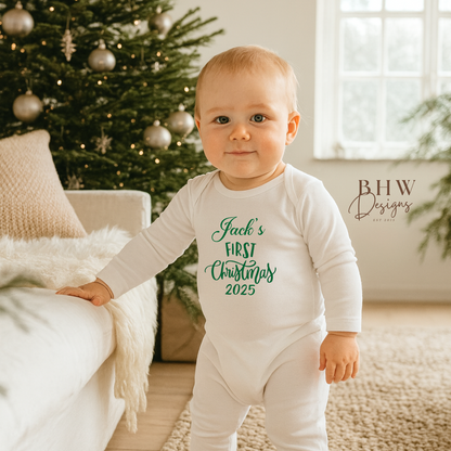 Baby wearing a onesie with 'Jack's First Christmas 2025' text, standing in a room with a decorated Christmas tree.