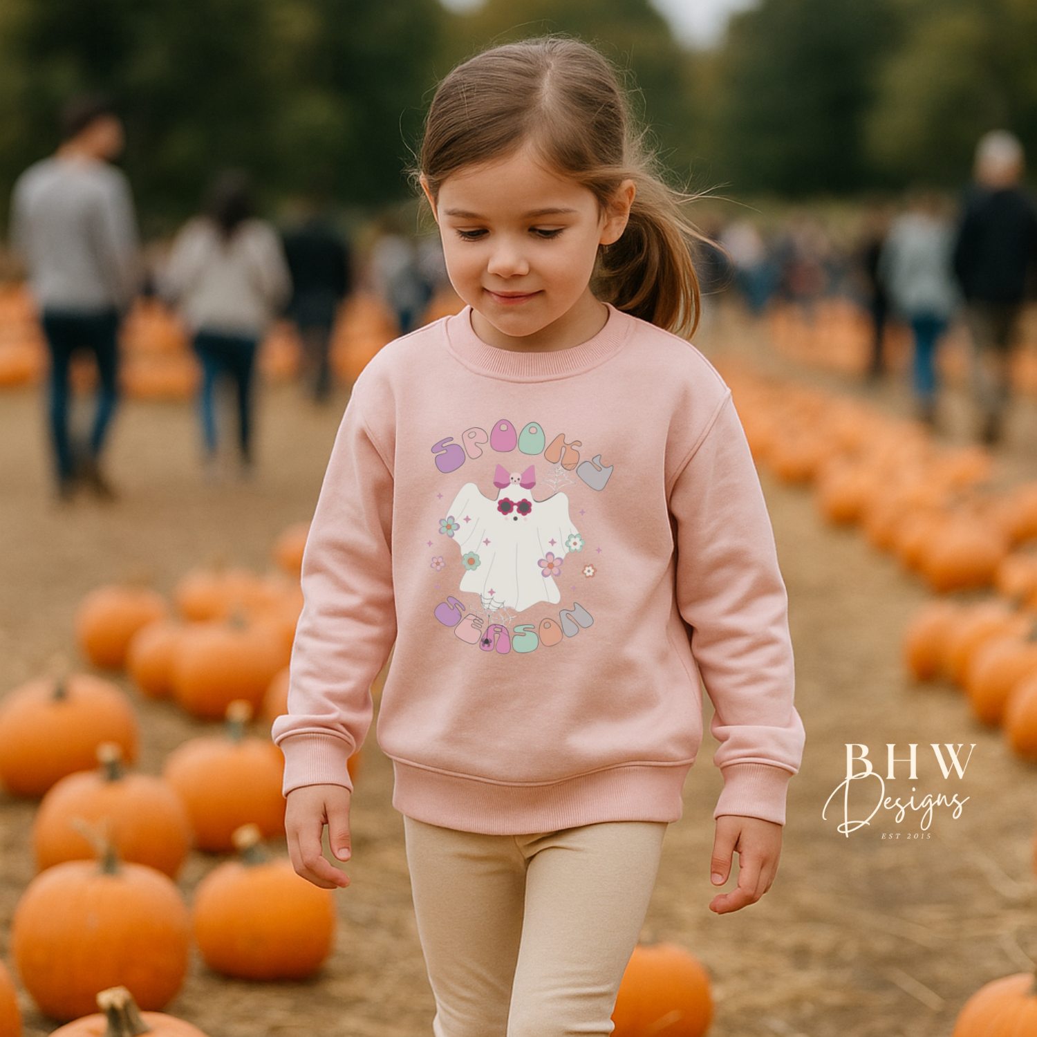 Young girl in a pink sweatshirt with a with spooky season ghost design on the front 