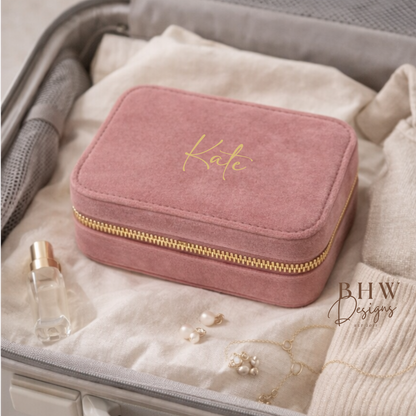 Pink jewellery box with gold zipper labeled 'Kate' inside an open suitcase with jewellery and a perfume bottle.